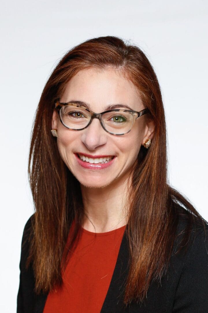 A woman with glasses and long hair wearing a red shirt.